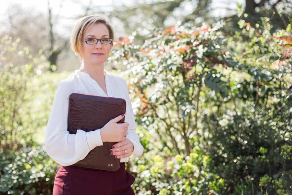 Woman holding a leather folder looking at the camera Kelly Chandler