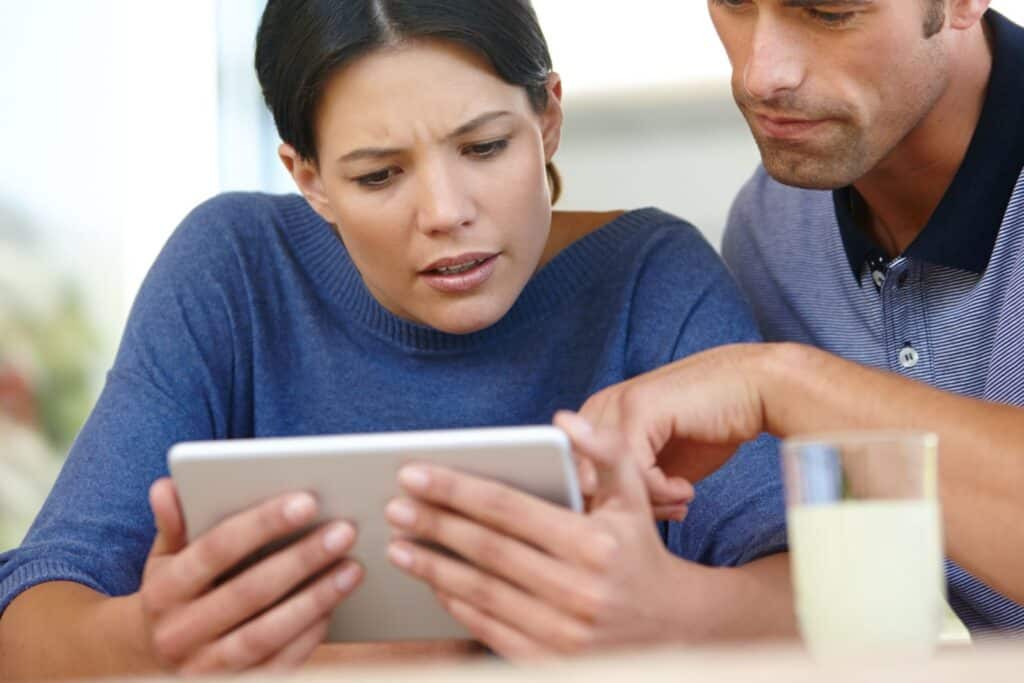 Concerned woman and man looking at a tablet together.