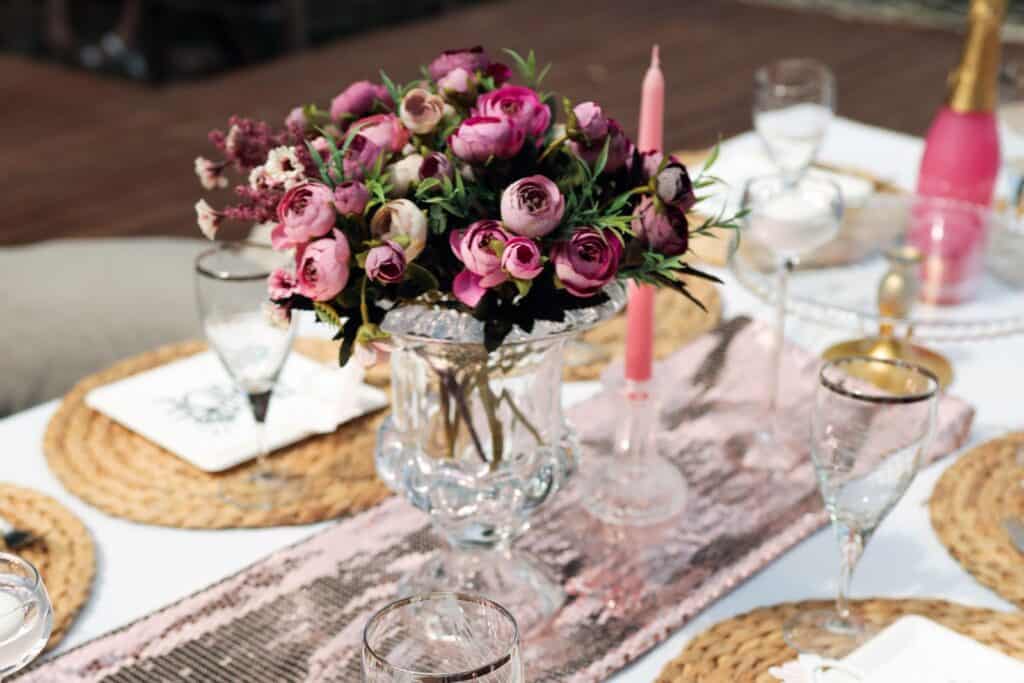 Elegant floral centrepiece with pink and purple flowers on a wedding table.