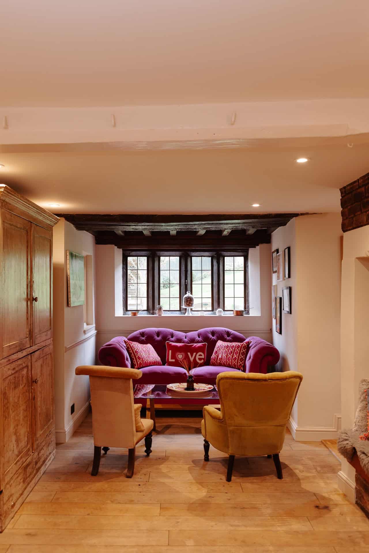 Cozy living room with purple sofa and yellow armchairs by window.