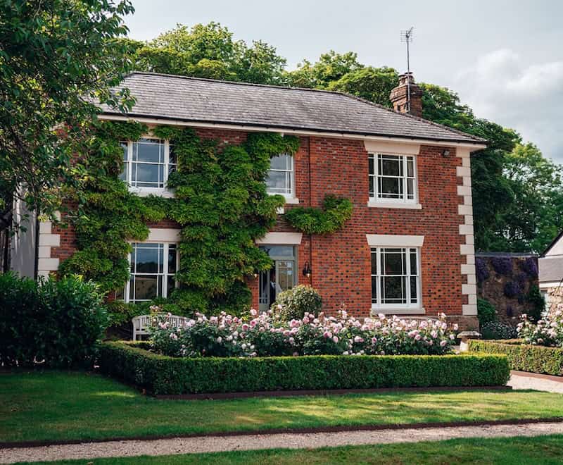 Traditional brick house with lush garden and climbing ivy in a peaceful neighbourhood.