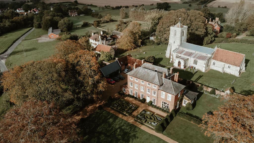 Aerial view of a historic village with a church and traditional buildings in autumn.