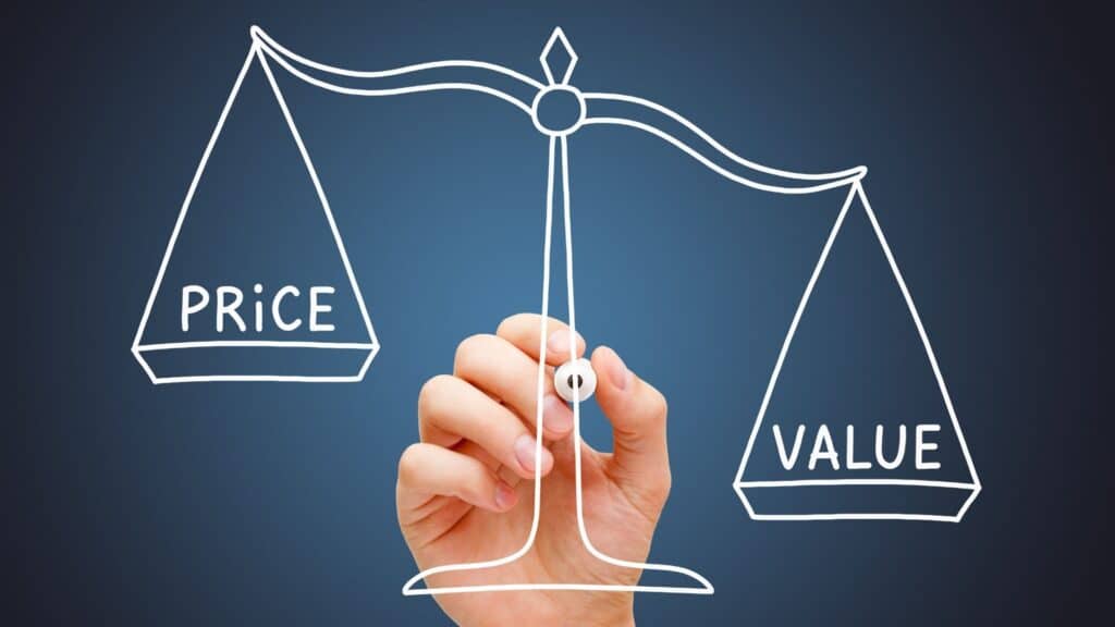 Hand drawing a balance scale with 'Price' and 'Value' on a chalkboard background.