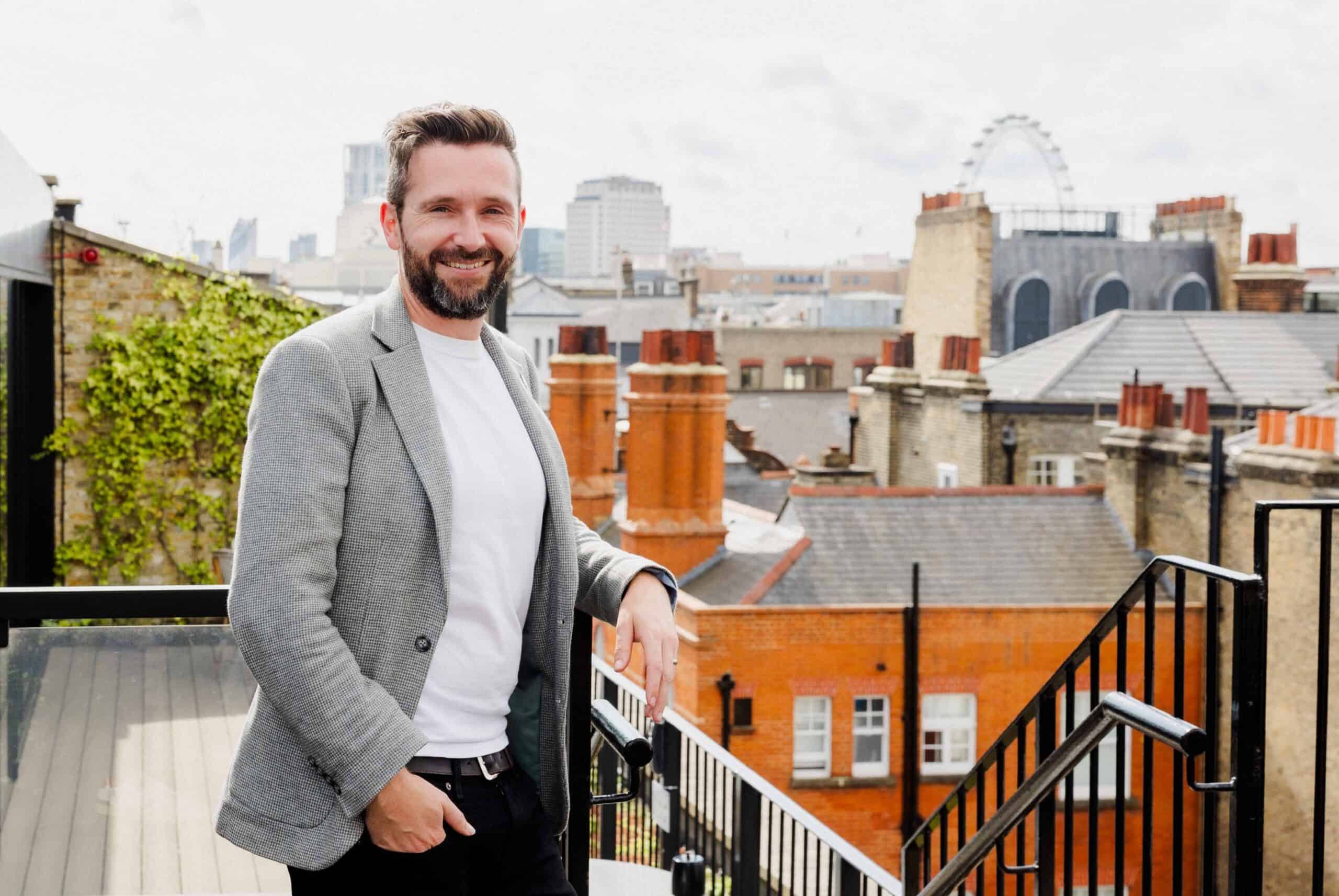 Kelly Chandler on a rooftop terrace with city skyline in background.