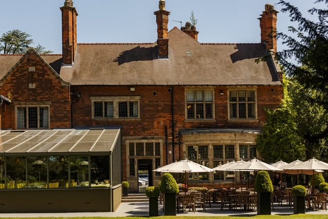 Historic brick building with outdoor dining area and glass conservatory.