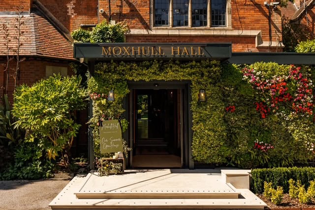 Moxhull Hall entrance with lush greenery and colourful flowers.