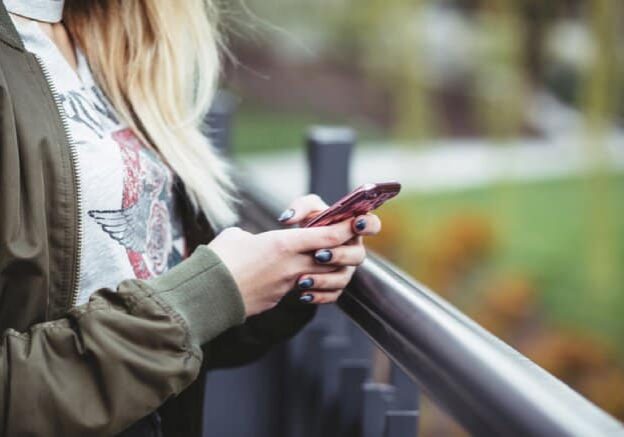 Lady on bridge looking at iphone | Kelly Chandler Consulting